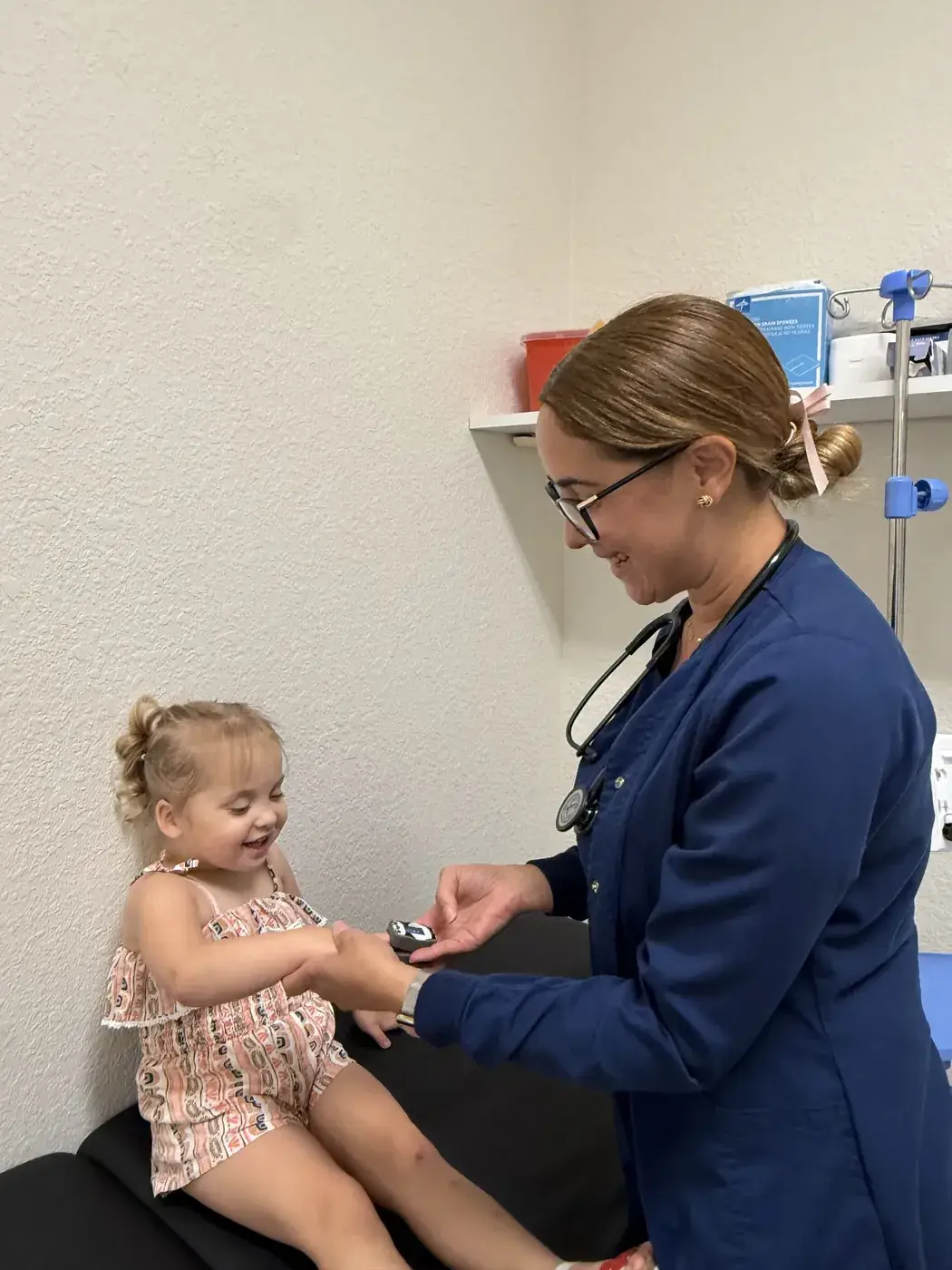 A nurse placing a pulse oximeter on a toddler's finger in the nursing area at Ellie's World PPEC in Port Charlotte, Florida