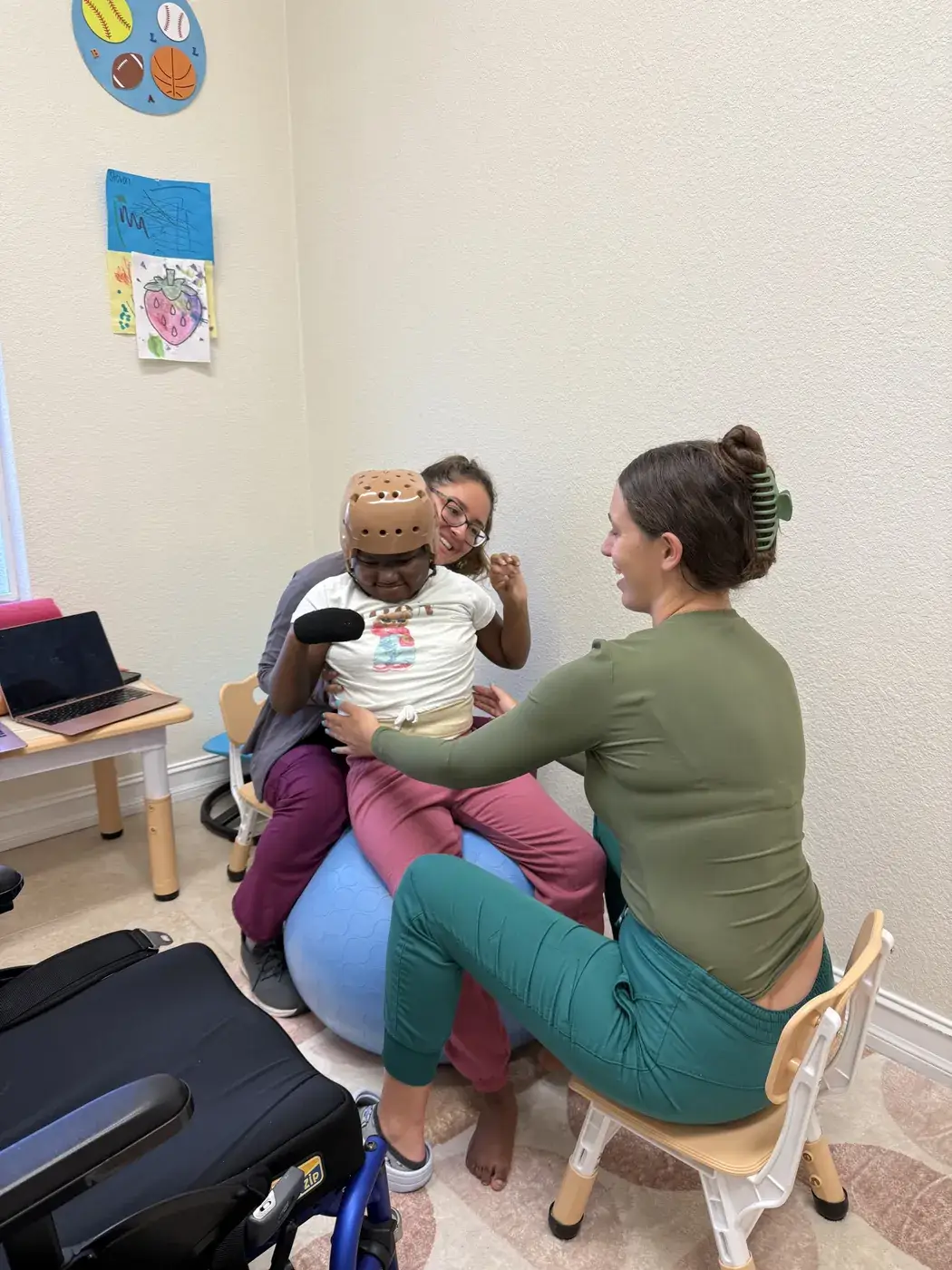 A physical therapist supporting a child on a therapy ball during a session at Ellie's World PPEC in Port Charlotte, Florida